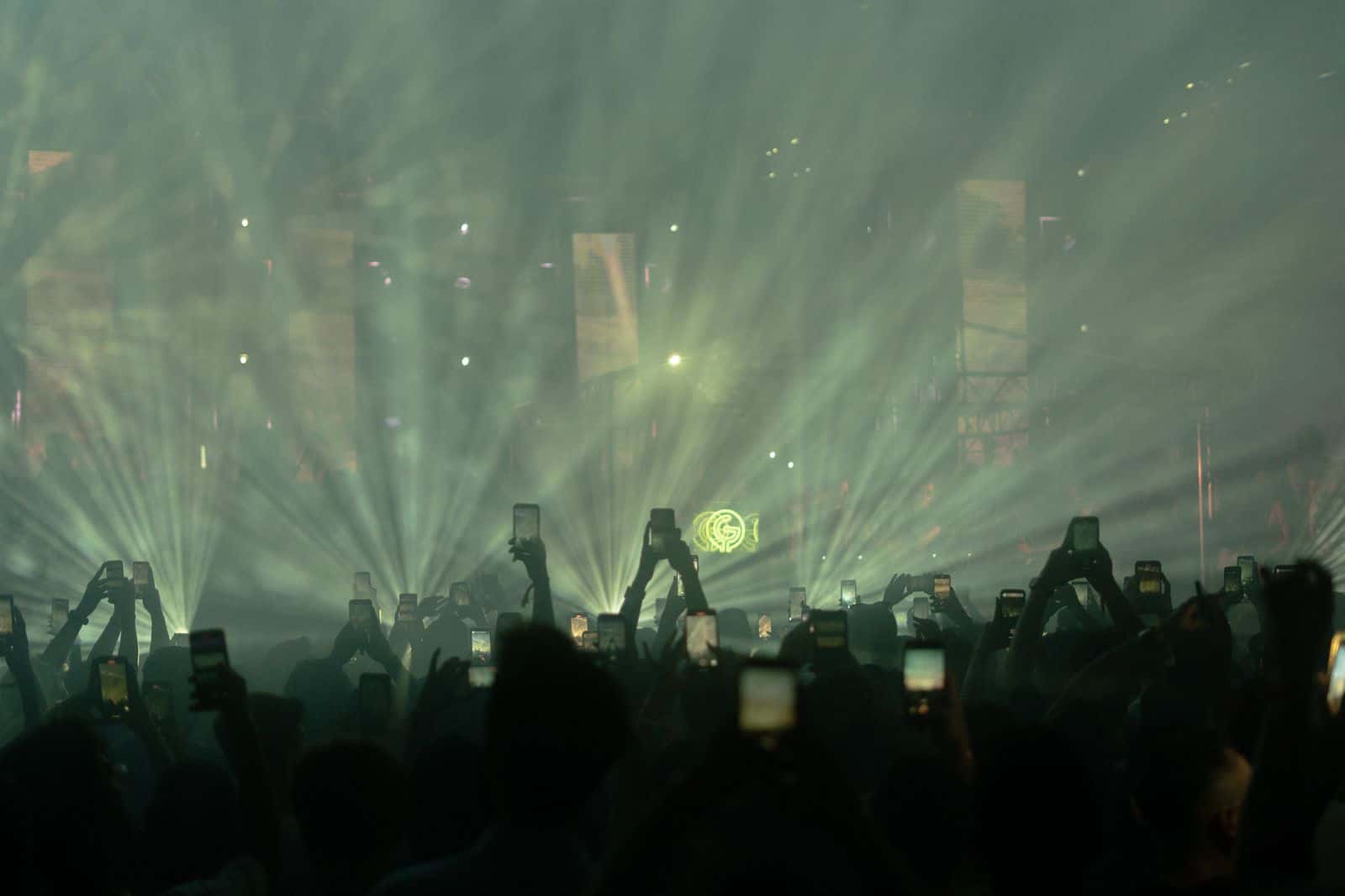 Concert crowd raising phones under stage lights