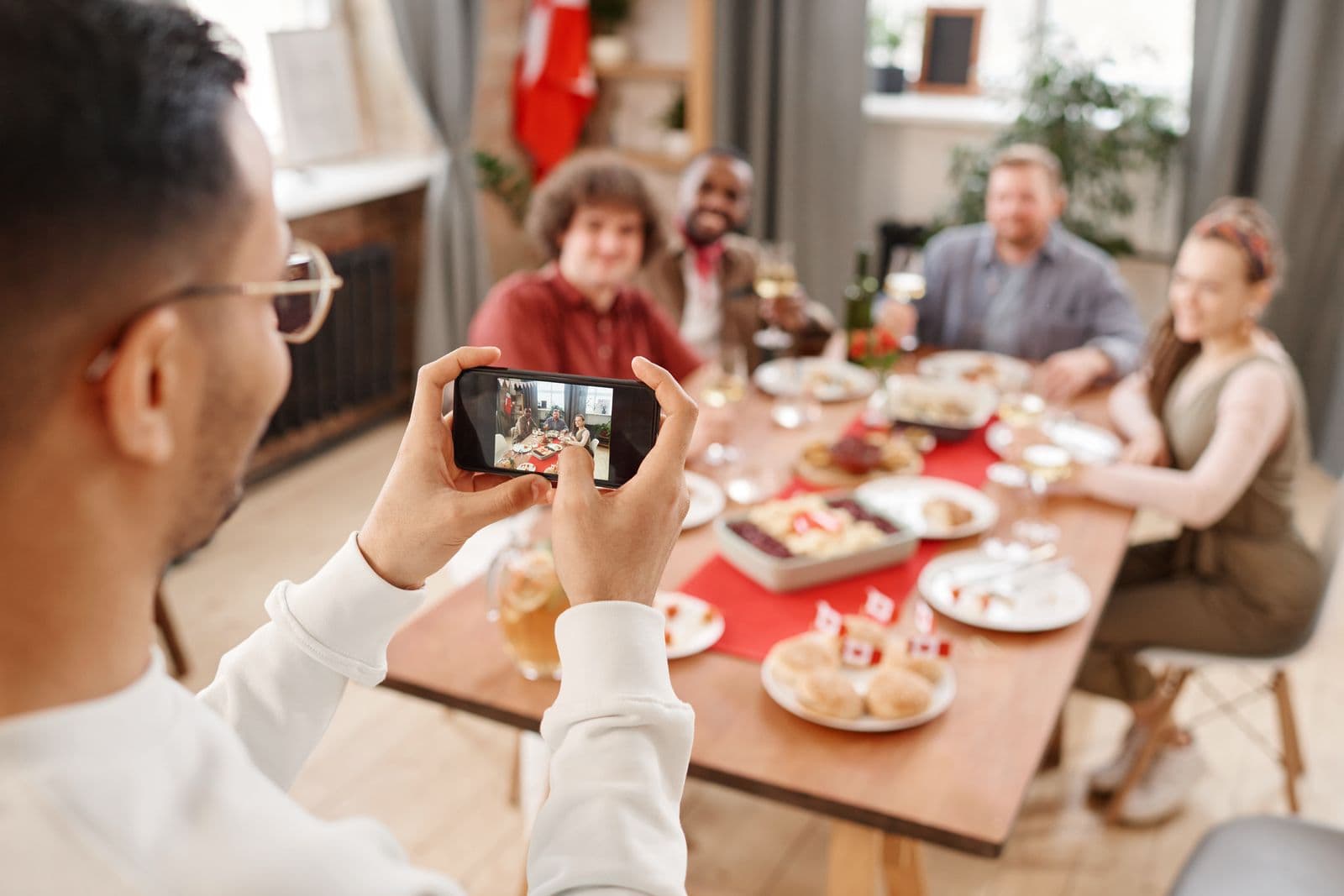 Guest using a phone to photograph friends around a dinner table